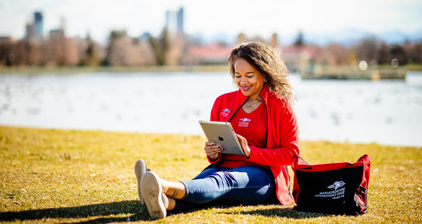 Student reading tablet outside.