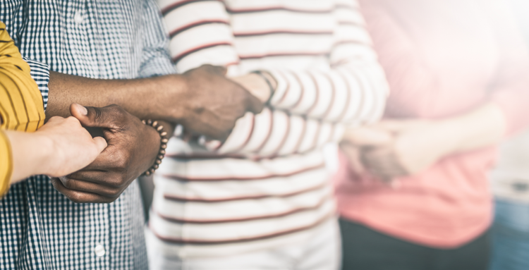 Four people standing in a line arms crossed holding hands