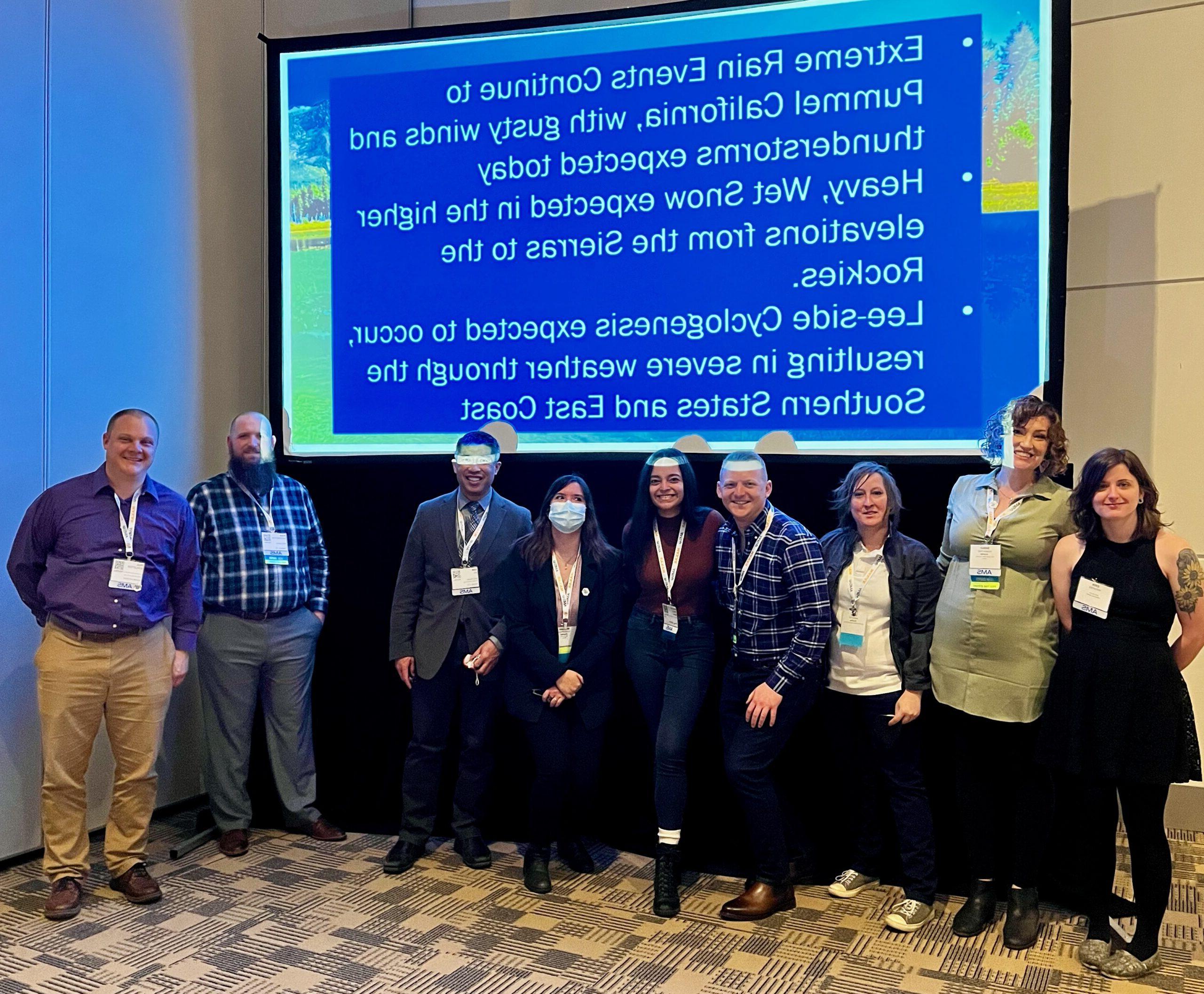 Students posing in front of a slide at the AMS conference after leading weather discussion