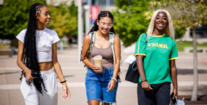 Three students walk together, smiling and laughing, outside on the MSU Denver campus