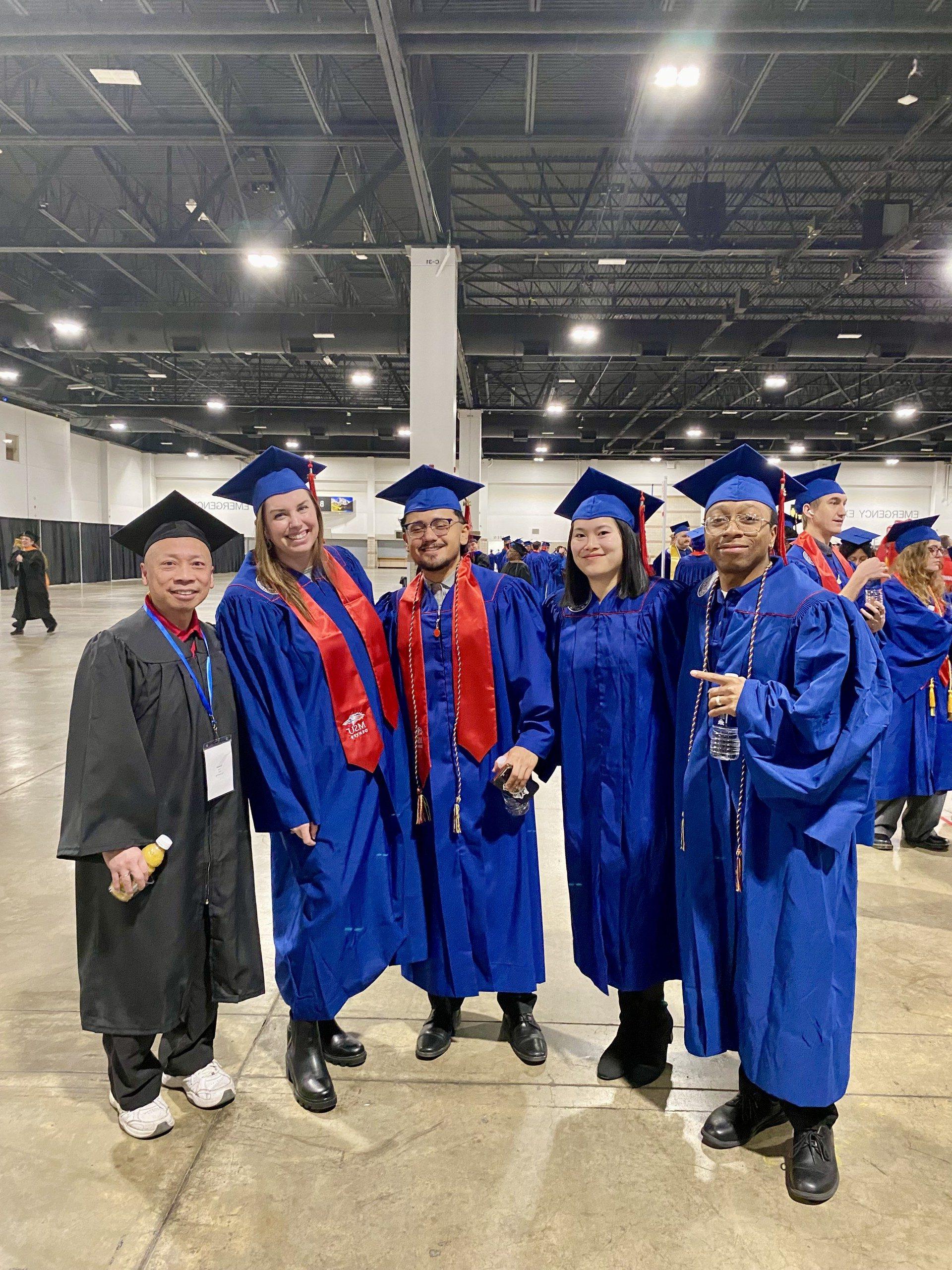 Acc advisor & 4 UG acc grads in regalia smiling at Fall '24 commencement